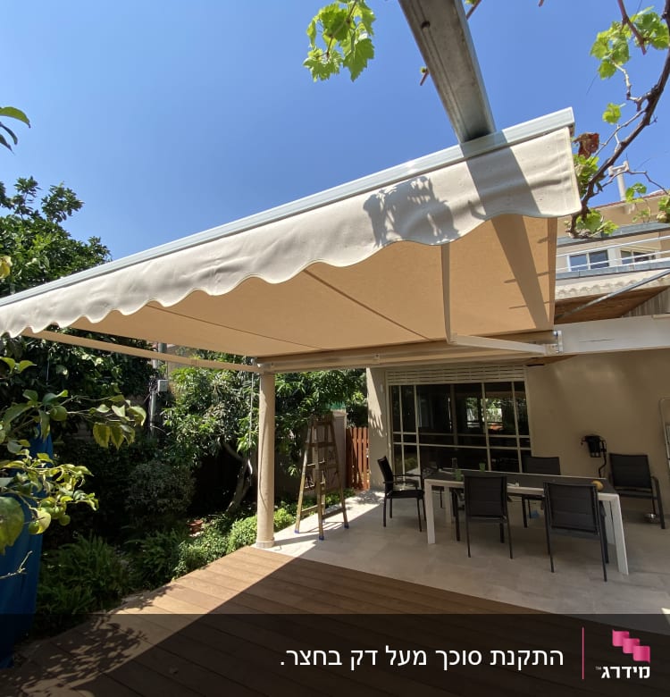 סוכך בד לבן על גינה עם שולחן וכיסאות